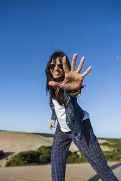 Low angle view of a similing woman showing the palm of her hand in a dune. .. Stock Photos