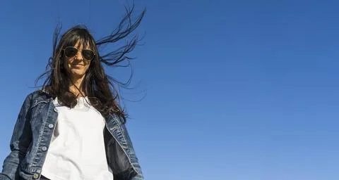Low angle view of a similing woman outdoors. Blue sky background. Stock Photos