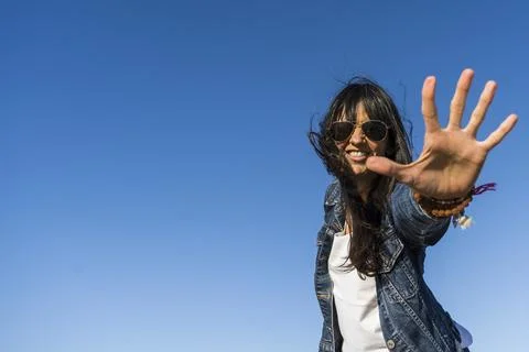 Low angle view of a similing woman while showing the palm of her hand.  Blu.. Stock Photos