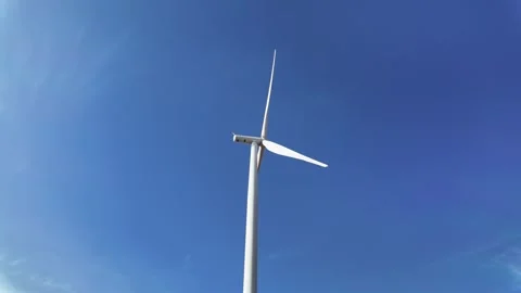 Low-angle view of a single wind turbine set against a vivid blue sky Stock-Footage 314817301
