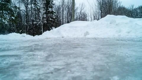 Low Angle View of Slippery Glare Ice Surface and Snow Banks in Winter Stock Photos