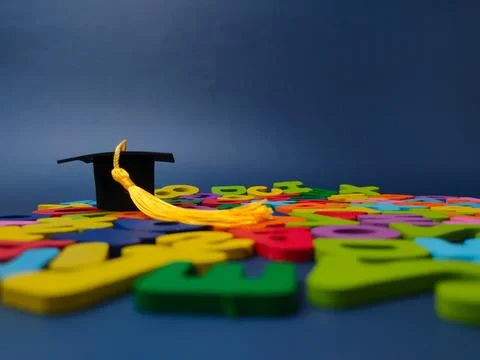 Low angle view of a small black graduation cap resting on a surface covered.. Stock Photos
