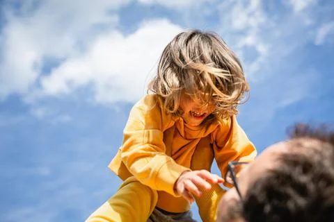 Low angle view on smiling child in yellow clothes watching father 스톡 사진