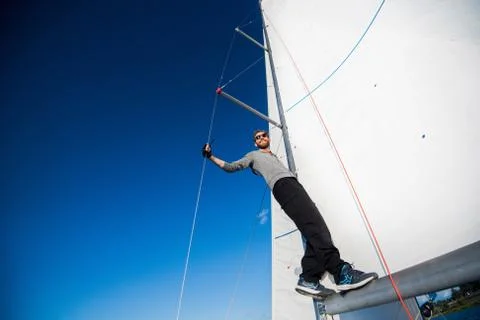 Low angle view of smiling man standing on yacht boom Stock Photos