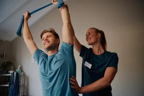 Low angle view of smiling young man doing exercises with beautiful young Stock Photos