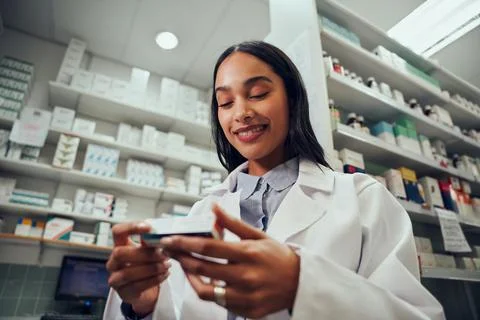 Low angle view of smiling young female working in chemist wearing labcoat Stock Photos