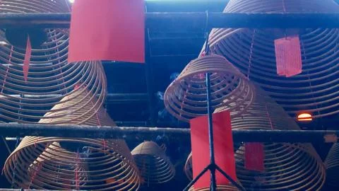 Low angle view of smoke emanating from spiral incense coils with red tags hung Stock Photos
