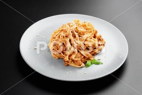 Low angle view of spaghetti bolognese with parmesan and purple basil, in a black Stock Photos