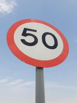 Low angle view of speed limit 50 mph sign board with sky in the background. Stock Photos