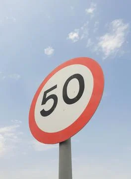 Low angle view of speed limit 50 mph sign board with sky in the background. Stock Photos