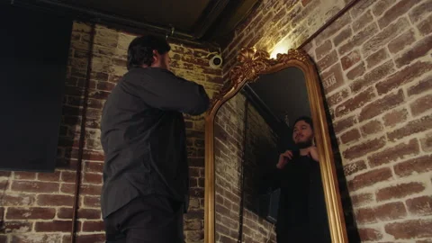 Low angle view of standing young man adjusting his hair and looking into mirror Video stock 331886971
