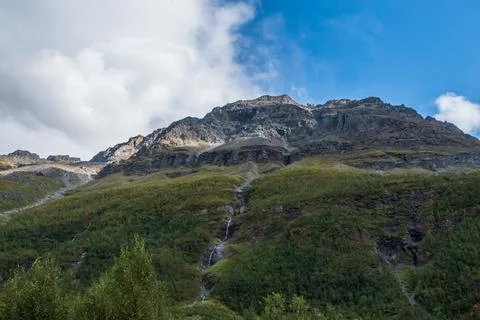 Low angle view of steep mountain side. Waterfall in the middle. Stock Photos