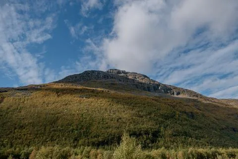 Low angle view of steep mountain. Beautiful blue sky with white clouds. Stock Photos