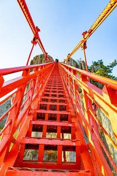 Low-angle view of a steep red stairway climbing toward towering cliffs at D.. Stock Photos