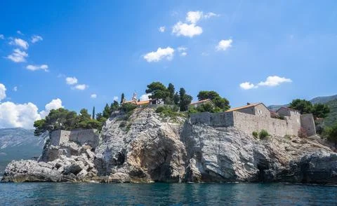 Low-angle view of stone fortification walls and buildings of Sveti Stefan ato Stock Photos