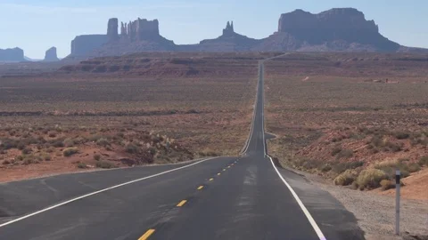 LOW ANGLE VIEW: Straight empty road leading to iconic Monument Valley Utah USA Stock Footage 77320817