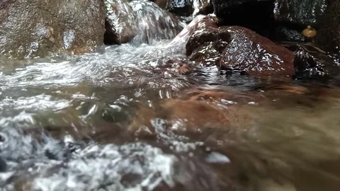 Low Angle View of Stream Flowing Around Brown River Boulder Stock Footage 329783120
