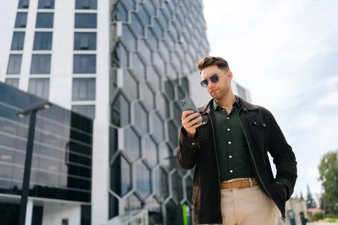 Low-angle view of stylish confident man in sunglasses using mobile phone Stock Photos