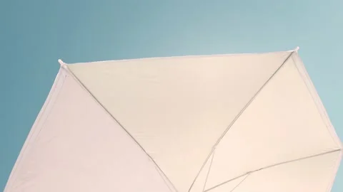 Low angle view of a Sun umbrella sunshade in a beach with blue sky in background Stock Footage 137791016