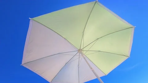 Low angle view of a Sun umbrella sunshade in a beach with blue sky in background Stock Footage 137791099