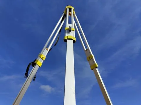 Low angle view of surveyor's tripod against clear blue sky Stock Photos