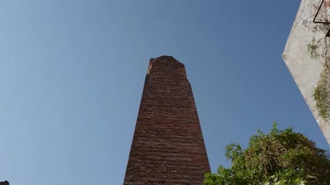 Low Angle View of Tall Brick Historic Tower Rising Against Clear Blue Sky in Stock Footage 346275334