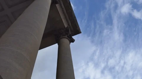 A low angle view of tall building columns under a blue sky with light clouds. Stock Footage 289880866
