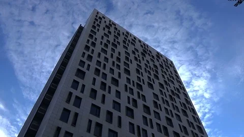 Low angle view on tall modern glass building on blue sky with white clouds Stock Footage 71656110