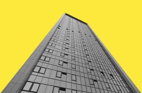 Low angle view of a tall modern skyscraper against a bright yellow background Stock Photos