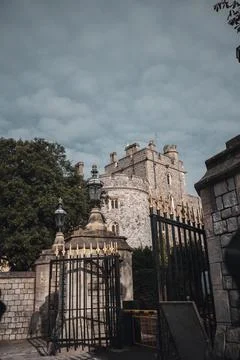 A low-angle view of a tall stone building with a black iron gate in the Stockfoto's