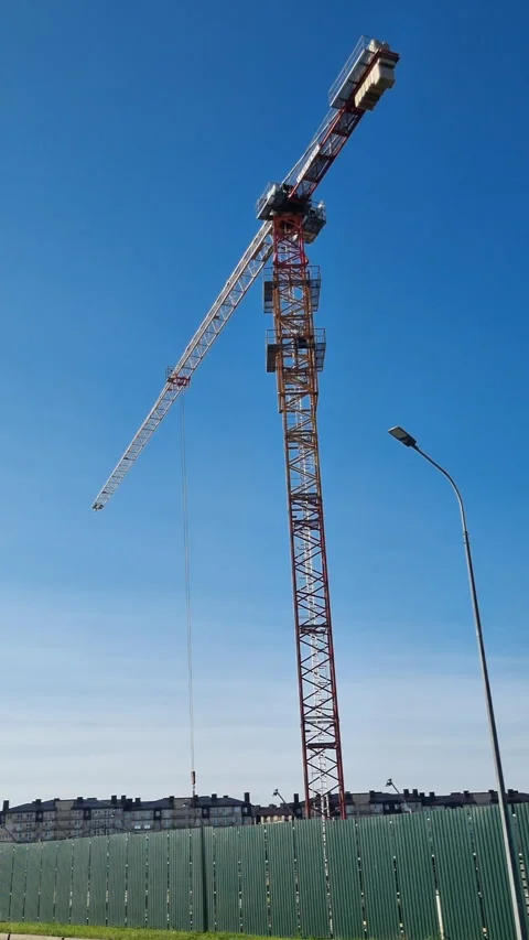 Low angle view of a tall tower crane working at a construction site against a cl Stock Footage 327158665
