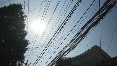 Low angle view of tangled power cables on electricity pylons by residential Stock Footage 117602905