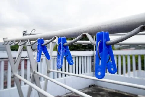 Low angle view of three blue plastic clothespins clipped onto the wavy bar .. Stock Photos