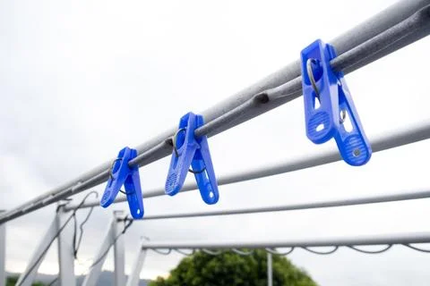 Low angle view of three blue plastic clothespins clipped onto a metal dryin.. Stock Photos