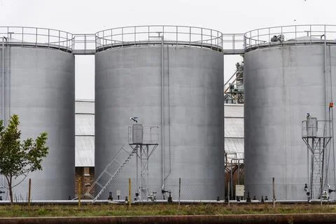 A low-angle view of three large, cylindrical tanks. Стоковые фото