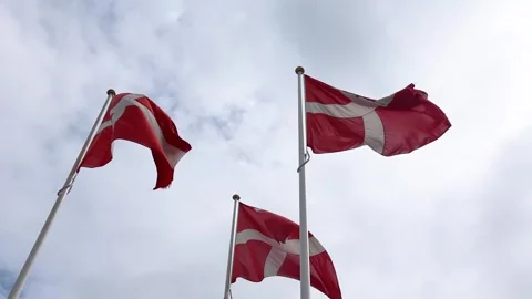 Low angle view of three national flags of Denmark waving in the wind against a Stock Footage 345758580