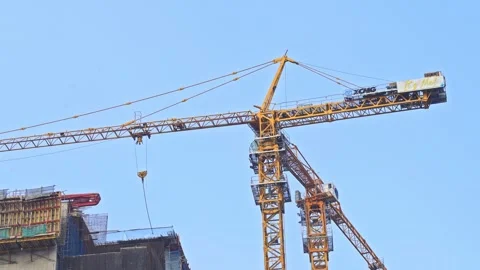 Low angle view of tower crane rotating over concrete high-rise structure Vidéo 339832751
