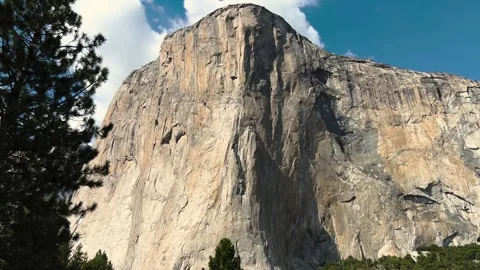 Low angle view of a towering granite cliff with pine trees in Yosemite Vill.. Video stock 348149368
