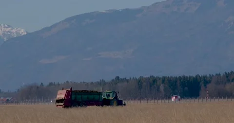 Low angle view of tractor with a trailer on farming field Stock Footage 171760768