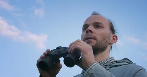 Low angle view of traveler looking into field-glass on blue sky background slow Vidéo 134701822
