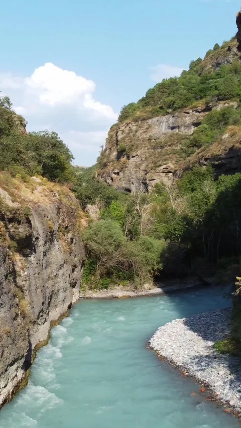 Low angle view of turquoise river flowing through deep rocky canyon with cliffs Stock Footage 336690660