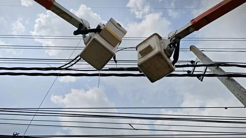 Low angle view of two aerial work platform bucket trucks repairing and join. Stock Photos