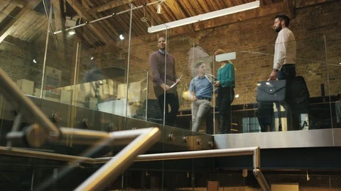 Low angle view of two businessmen greeting and talking in office corridor Stock Footage 107904878