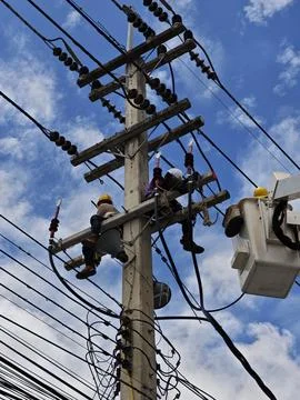Low angle view of two lineman electricians sitting on utility riser pole. Stock Photos
