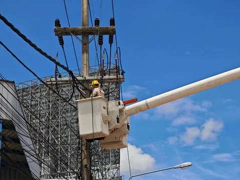 Low angle view of two lineman electricians sitting on utility riser pole. Stock Photos
