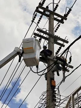 Low angle view of two lineman electricians sitting on utility riser pole. Stock Photos