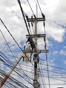 Low angle view of two lineman electricians sitting on utility riser pole. Stock Photos