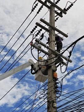 Low angle view of two lineman electricians sitting on utility riser pole. Stock Photos