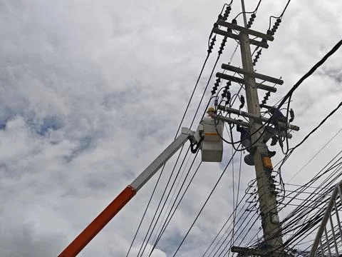 Low angle view of two lineman electricians sitting on utility riser pole. Stock Photos