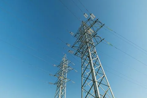 Low angle view of two steel electricity pylons with power lines against cle.. Stockfoto's